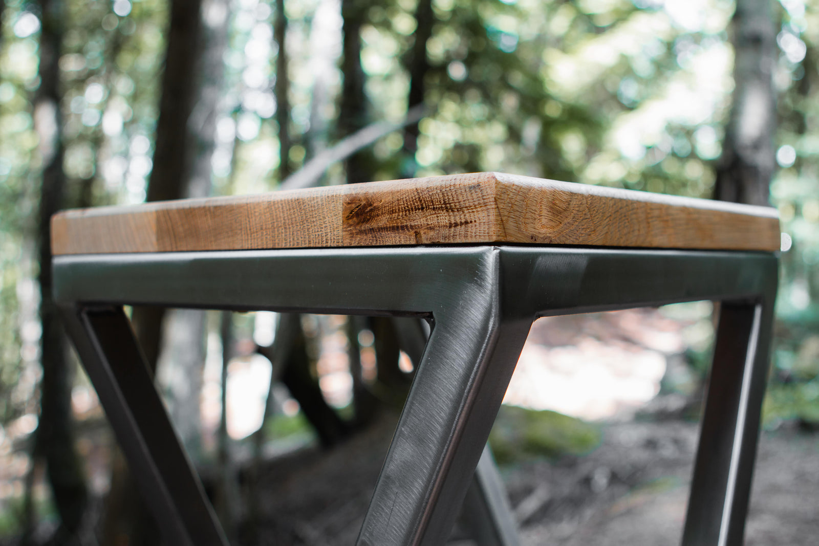 Wooden table with metal legs in a forest setting