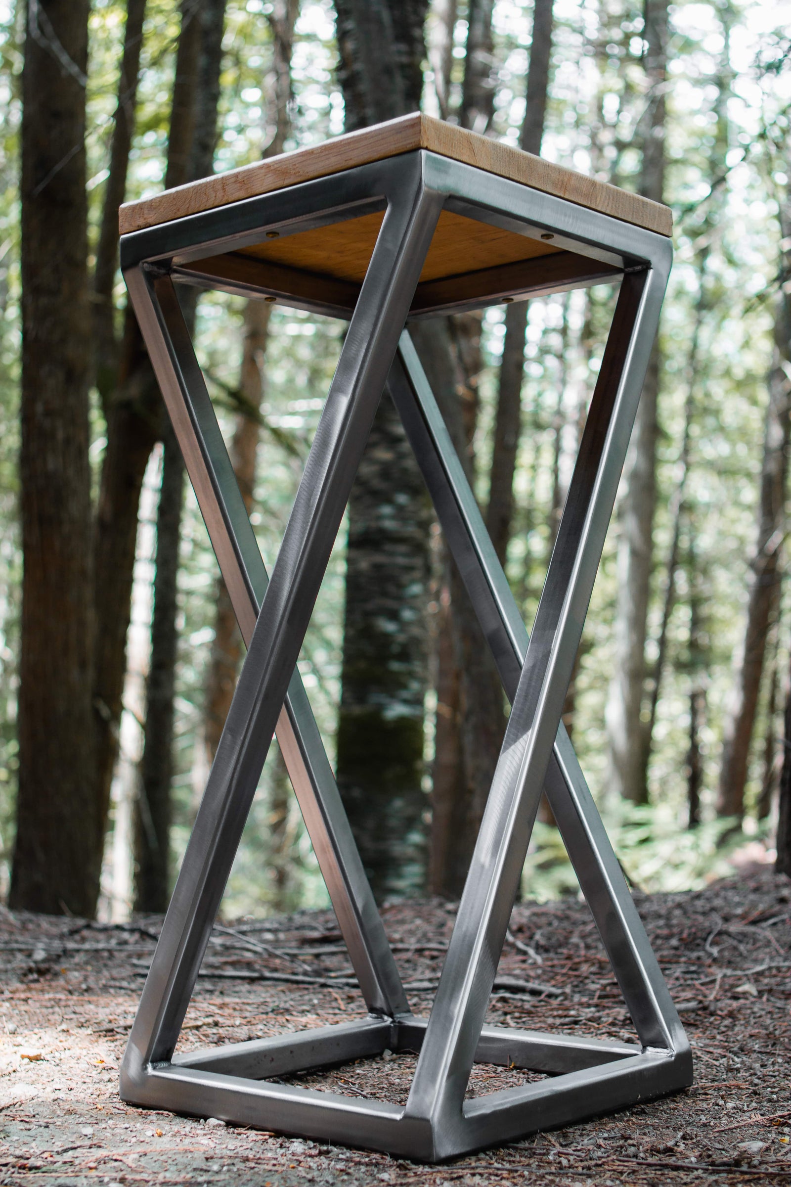 Modern metal stool with wooden top in a forest setting
