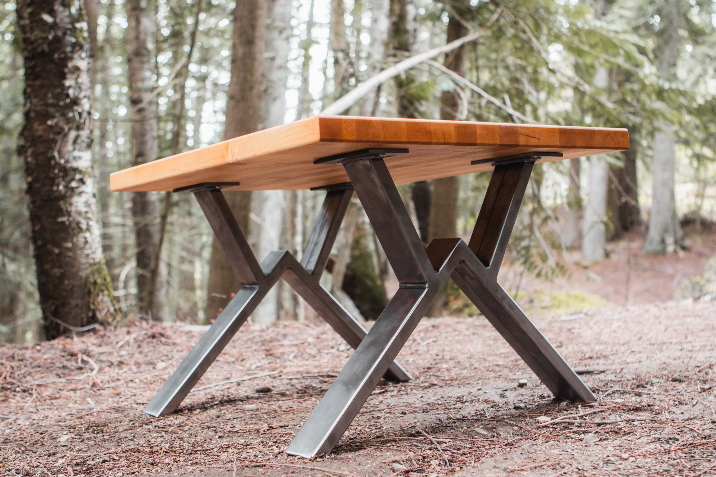 Wooden table with metal legs in a forest setting