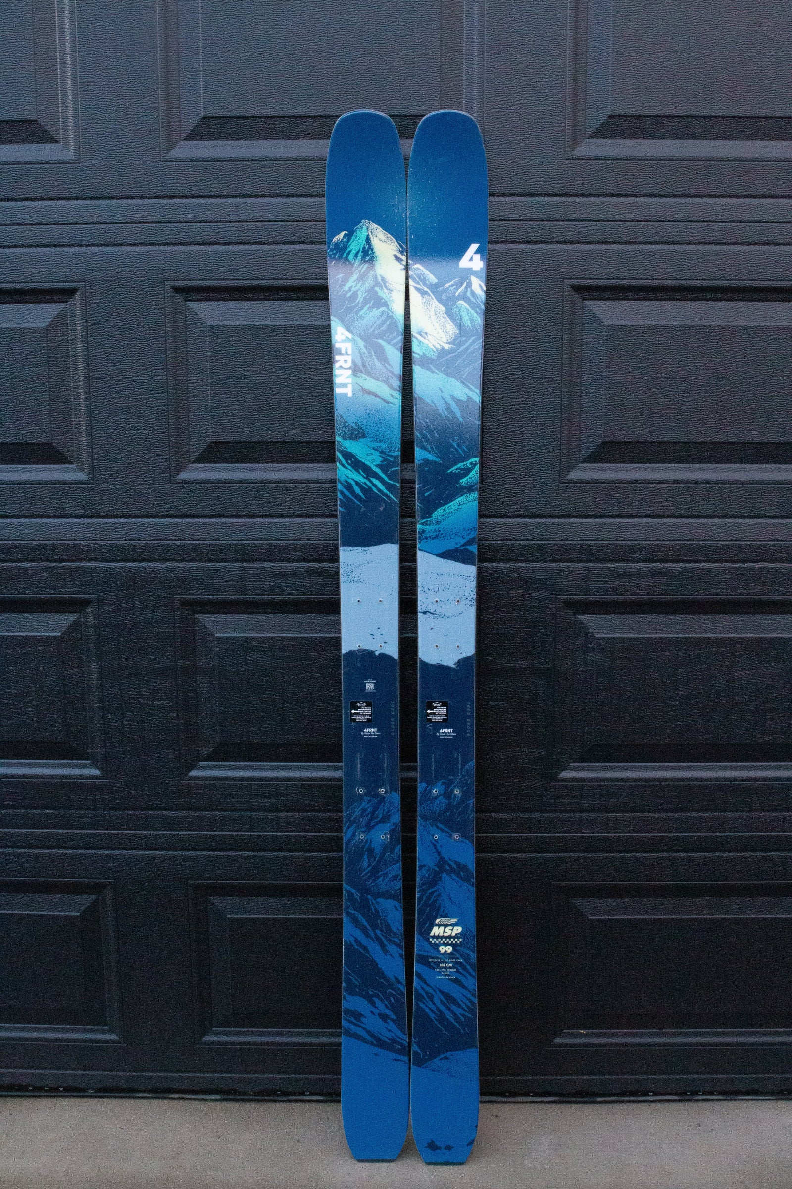 Blue skis with mountain design against a dark background