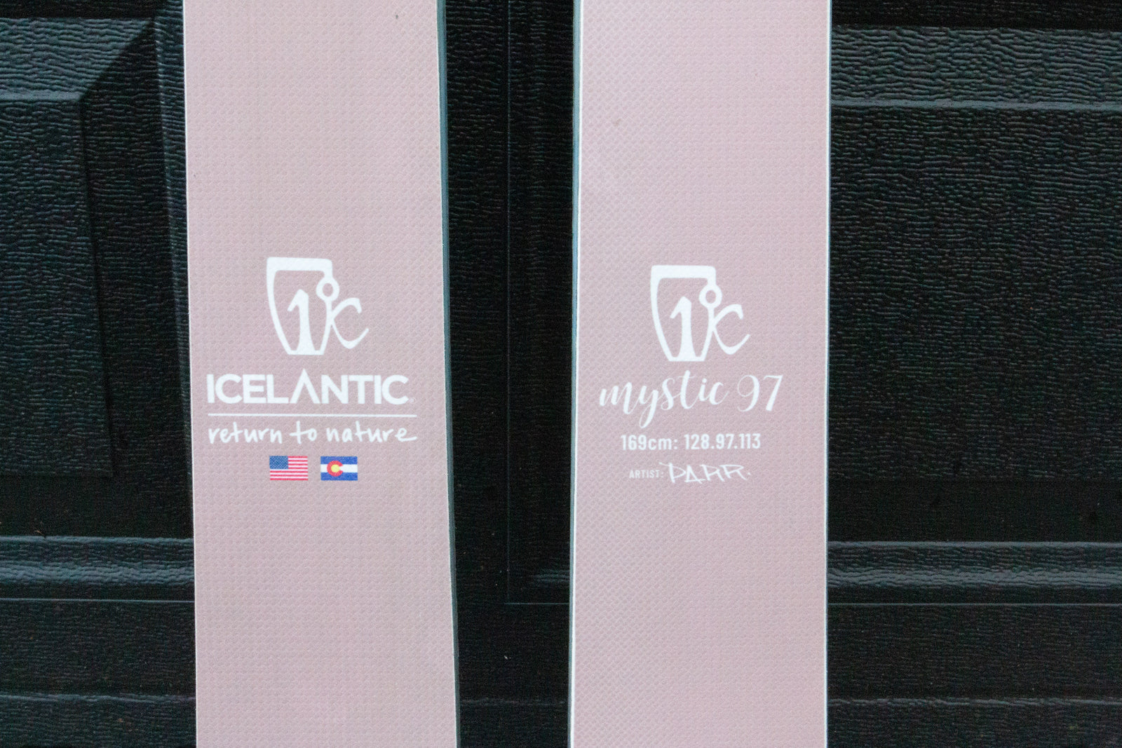 Two pink skis with 'Icelantic' branding on a black background