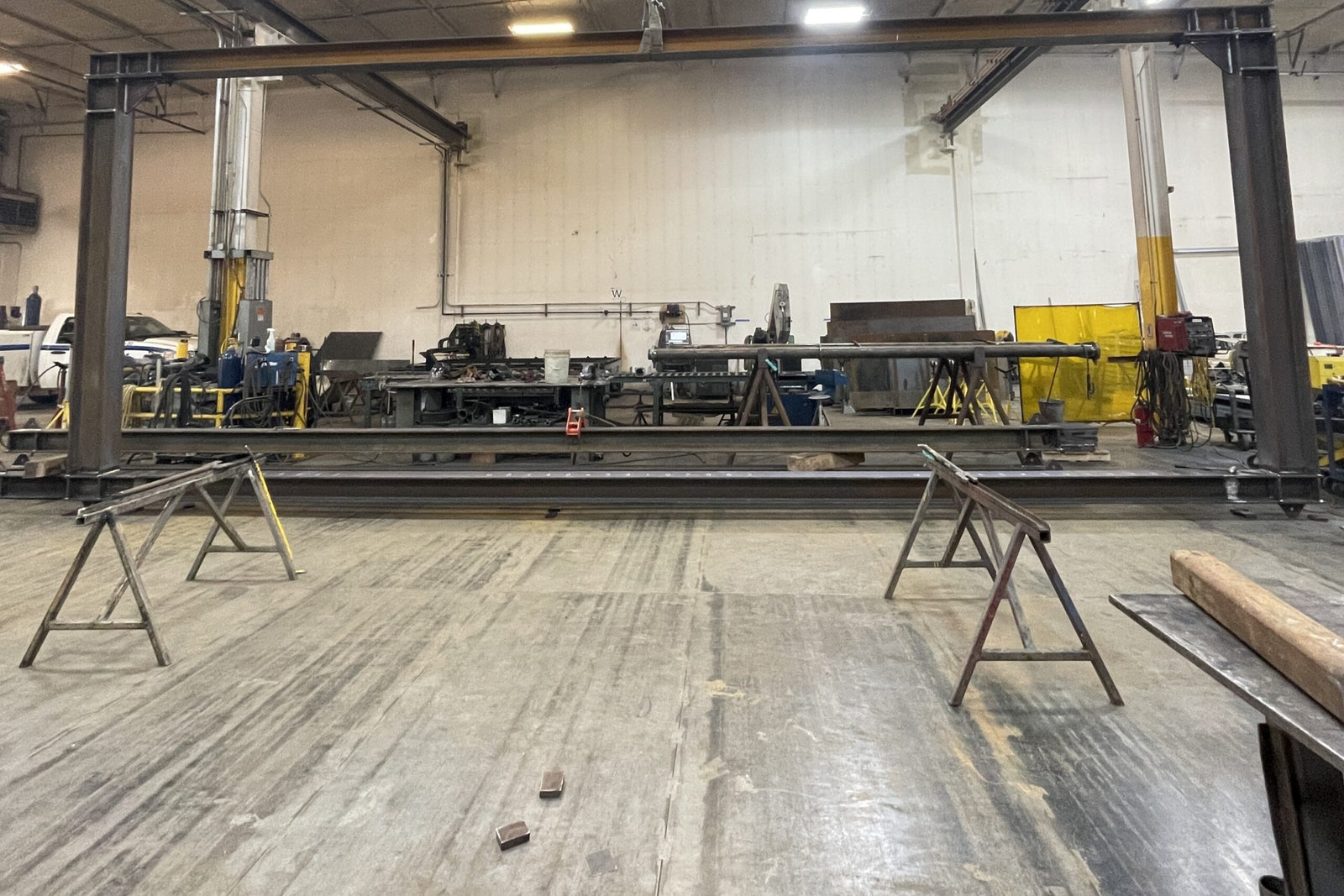 Warehouse interior with metal frames and equipment on a wooden floor.