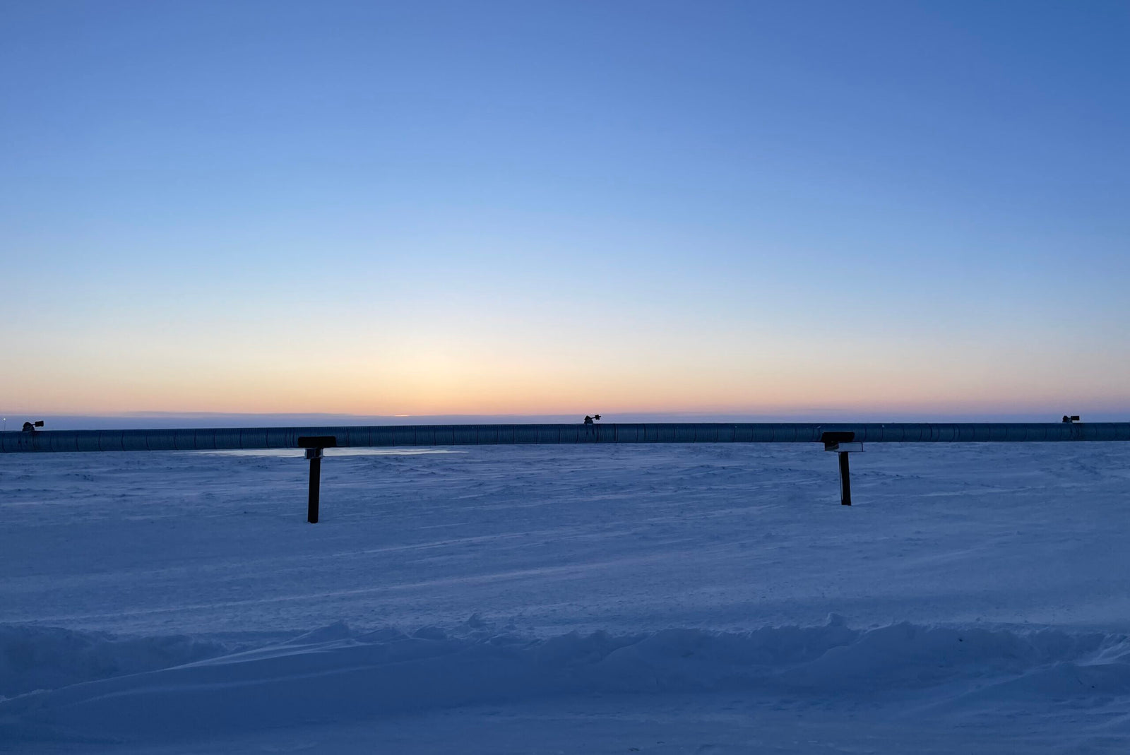 Snowy landscape with a clear sky during sunset or sunrise.