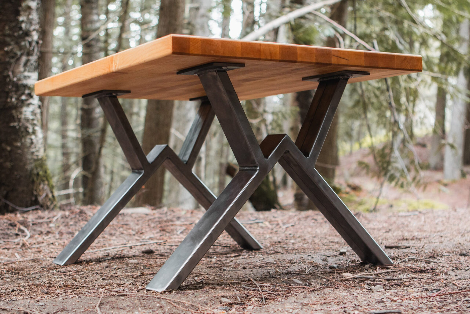 Wooden table with metal legs in a forest setting