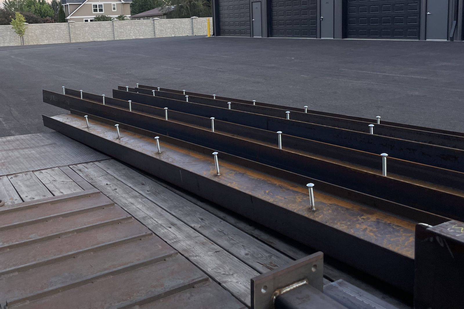 Long metal beam on a concrete surface with a building in the background