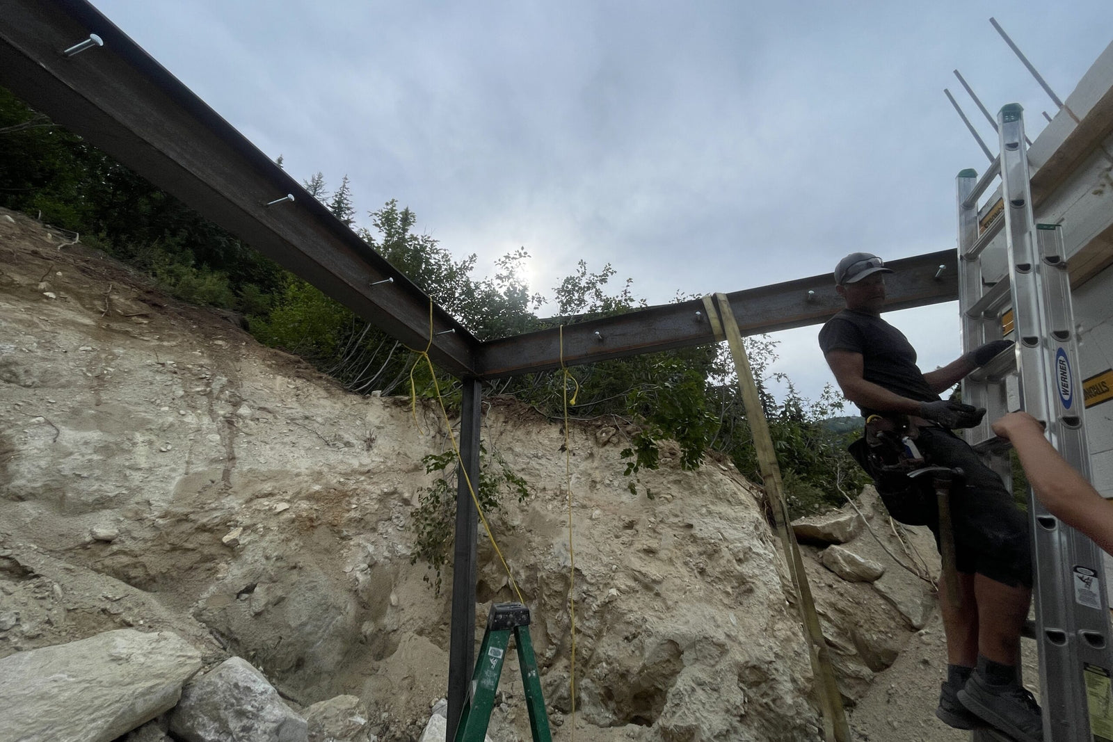 Person working on a construction site with a ladder and metal beams.