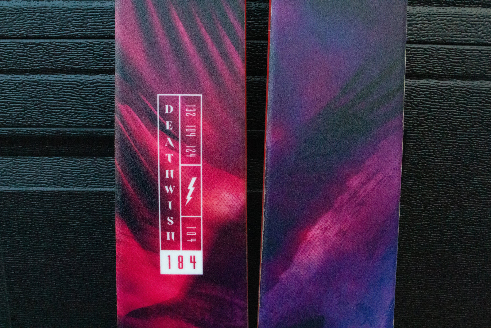 Purple and red Skis with 'Deathwish' logo on a dark background