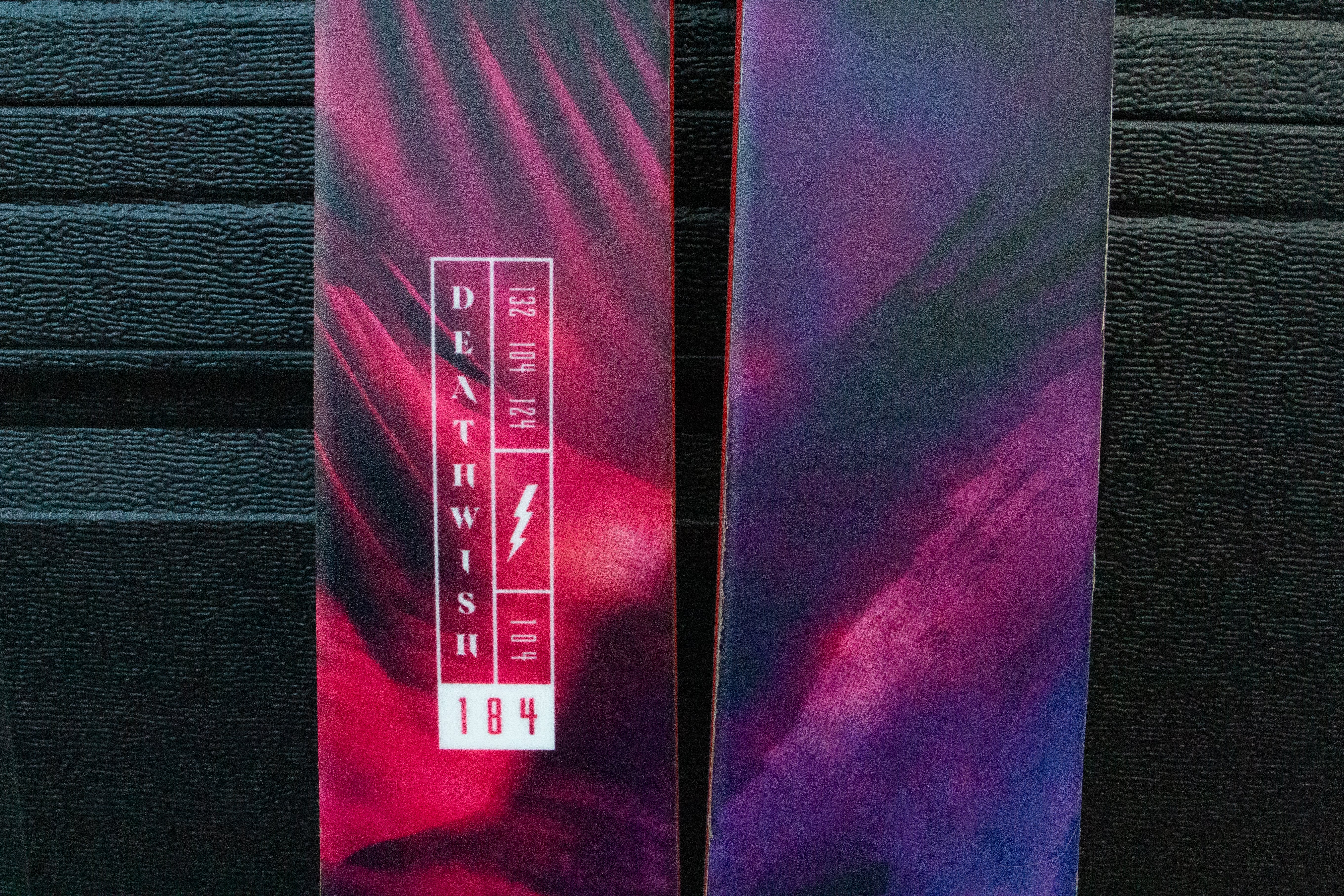 Purple and red Skis with 'Deathwish' logo on a dark background