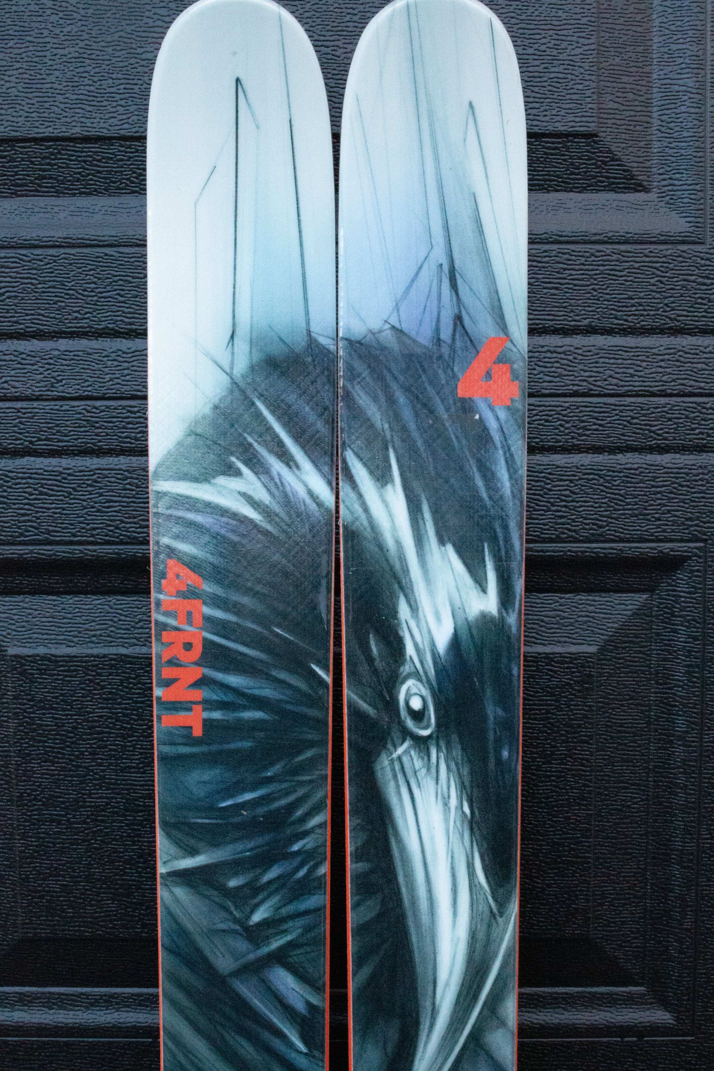 Skis with a raven design and '4FRNT' branding on a textured black background