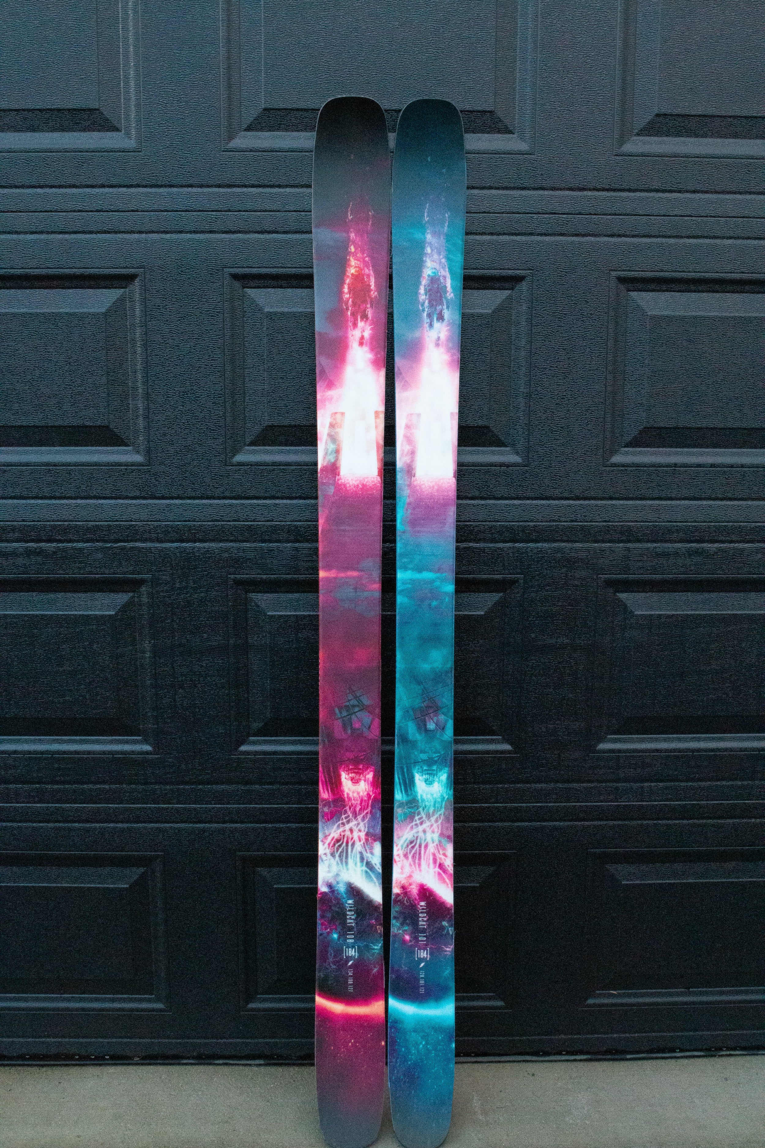 Two colorful skis against a dark textured wall