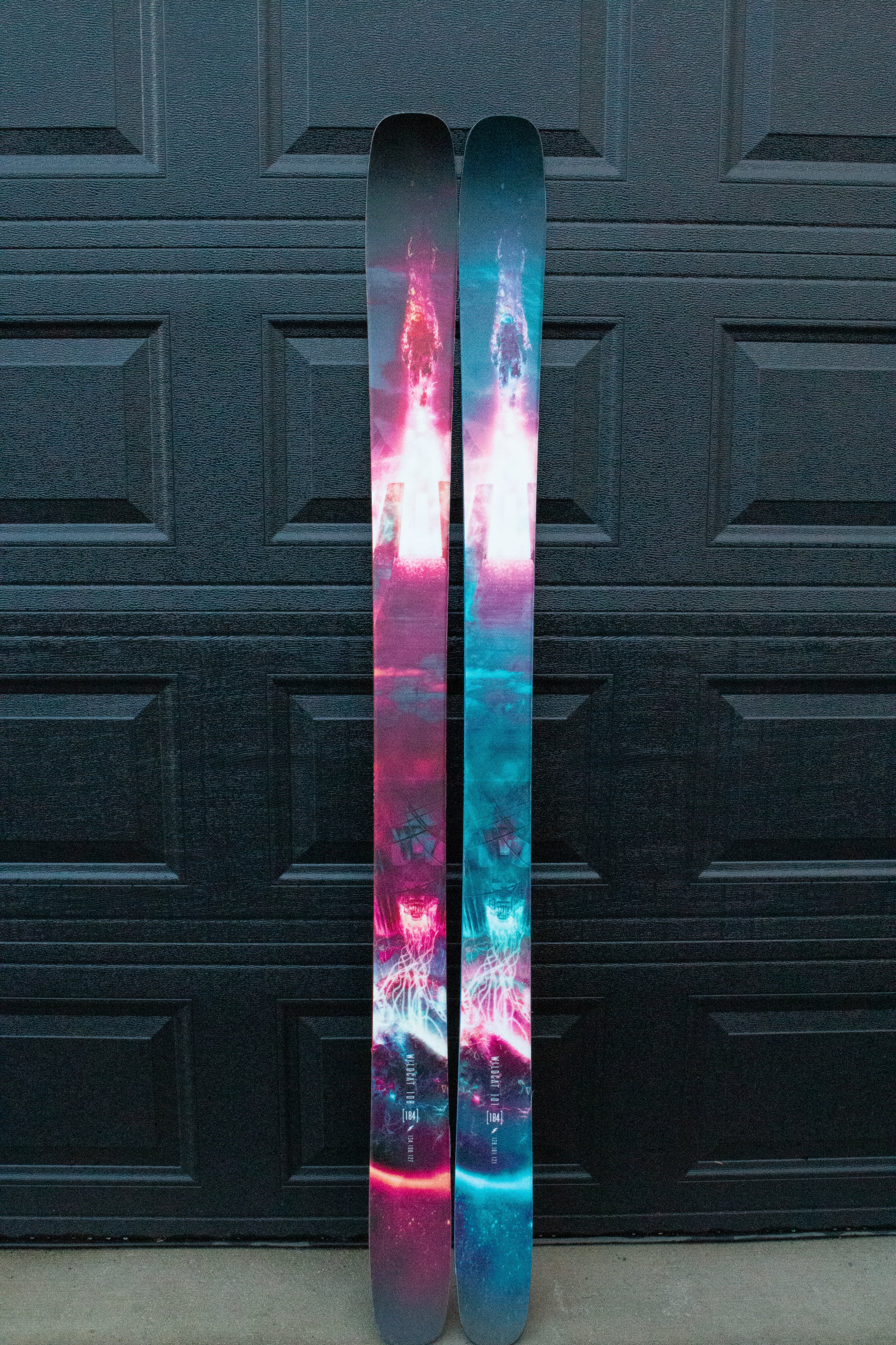 Two colorful skis against a dark textured wall