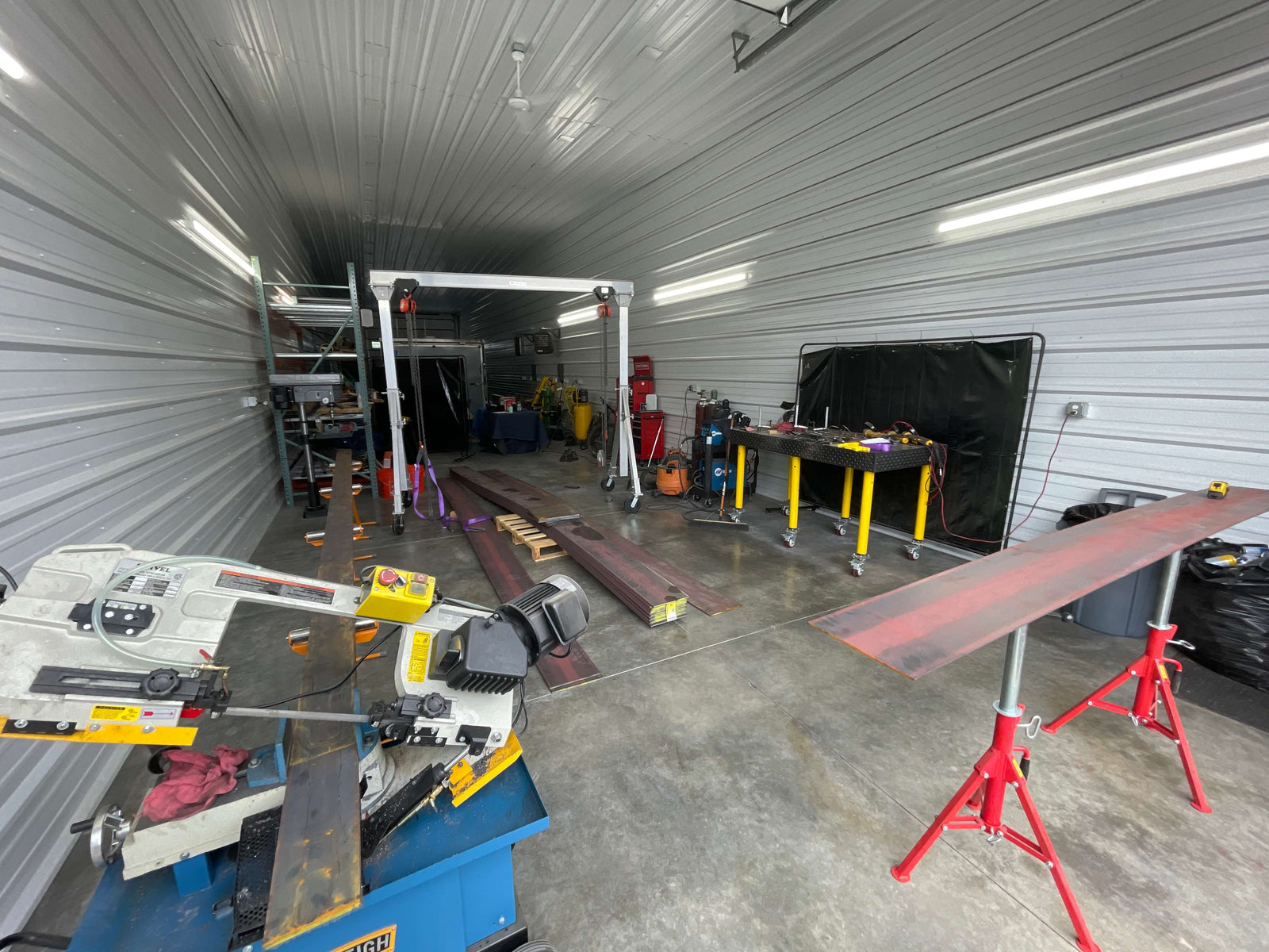 Garage workshop with tools, equipment, and materials on a concrete floor.